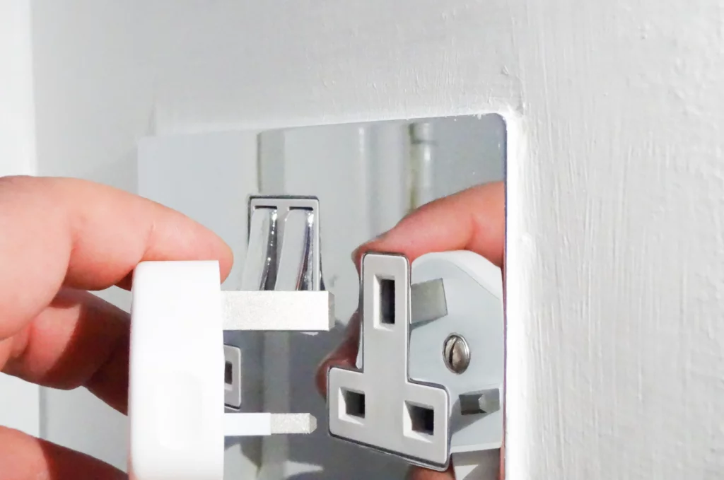 Person inserting a plug into a wall socket