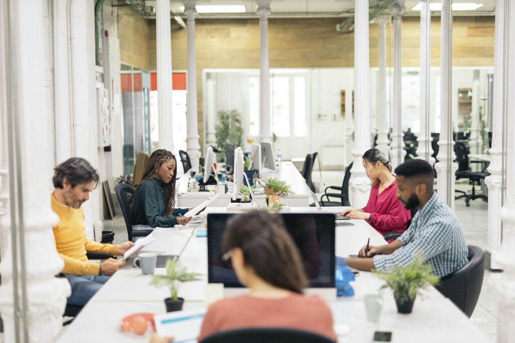 People working in a large office with modern lighting solutions to boost employee productivity