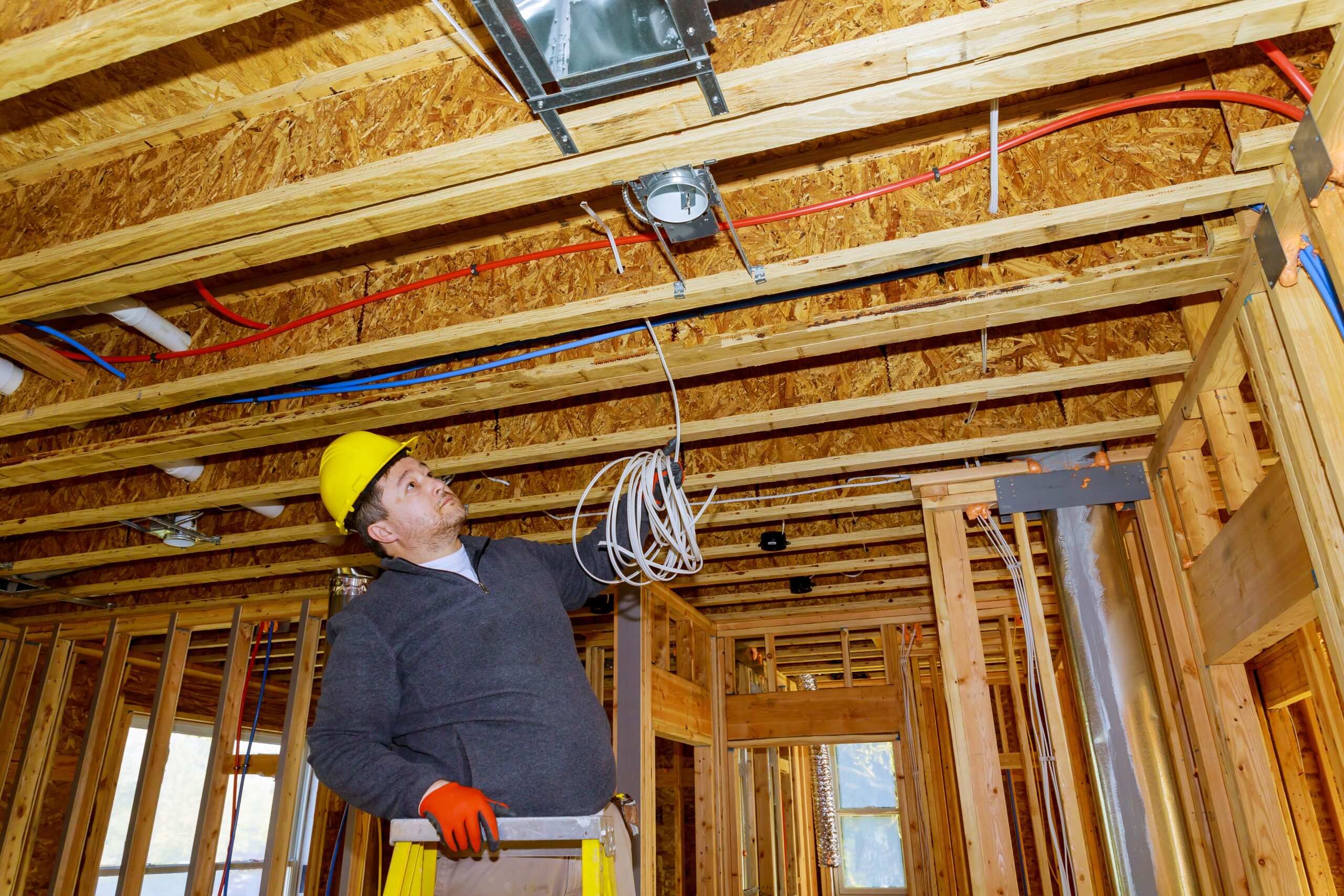 Contractor Electrician installing electrical cable wire in unfinished room